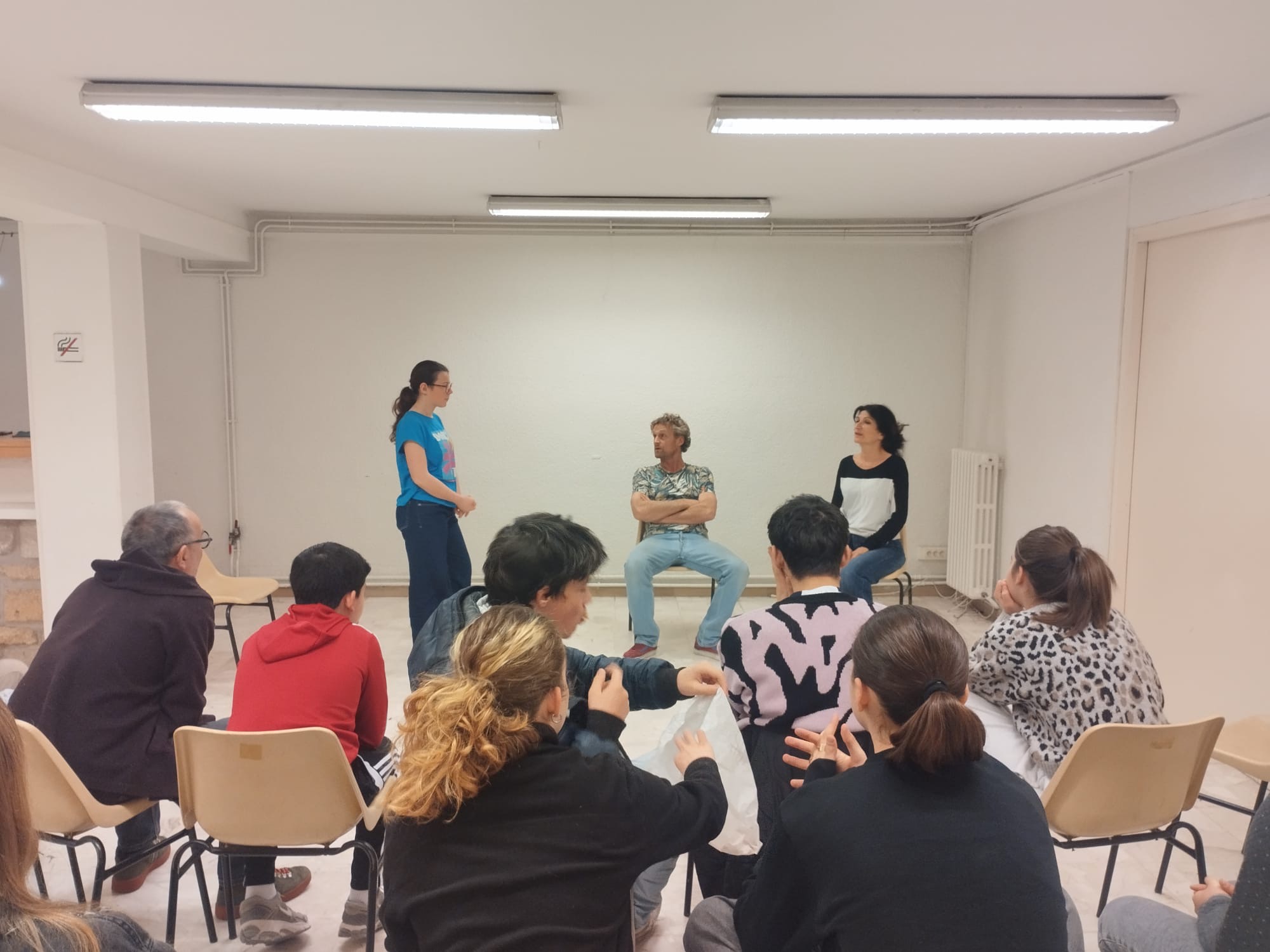 Atelier de théâtre forum : trois comédiens jouent une scène devant un groupe de participants